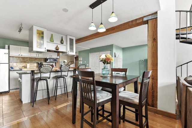 dining space with light wood-type flooring and beam ceiling