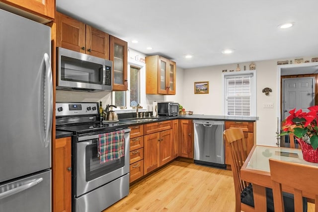 kitchen featuring kitchen peninsula, appliances with stainless steel finishes, light hardwood / wood-style floors, and sink