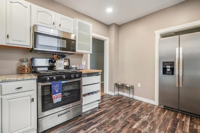 kitchen featuring light stone countertops, white cabinetry, dark wood-type flooring, and appliances with stainless steel finishes