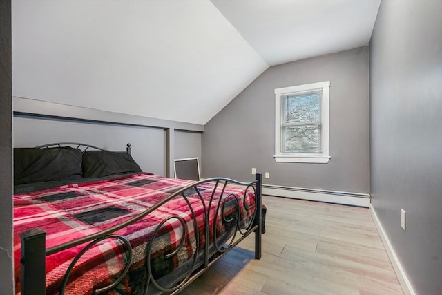 bedroom with lofted ceiling, a baseboard radiator, and light hardwood / wood-style floors