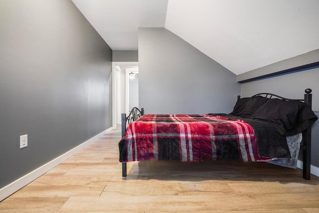 bedroom featuring light wood-type flooring and vaulted ceiling