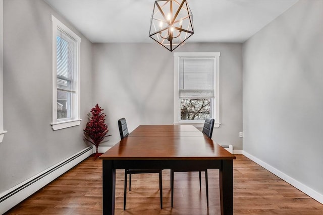 dining room featuring a healthy amount of sunlight, a baseboard radiator, and a notable chandelier