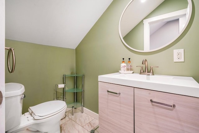 bathroom featuring vanity, toilet, and vaulted ceiling