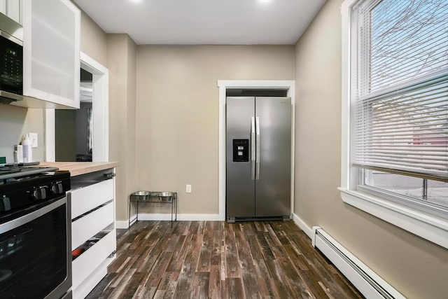 kitchen with wood counters, dark wood-type flooring, appliances with stainless steel finishes, a baseboard radiator, and white cabinetry