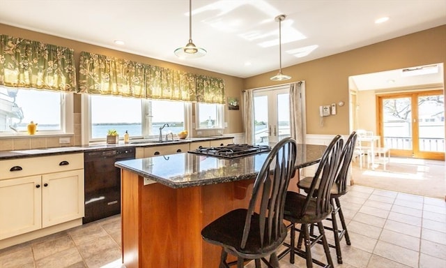 kitchen featuring pendant lighting, a water view, black dishwasher, and dark stone counters