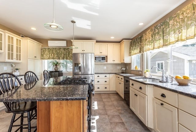 kitchen with sink, stainless steel appliances, dark stone counters, a kitchen bar, and a kitchen island