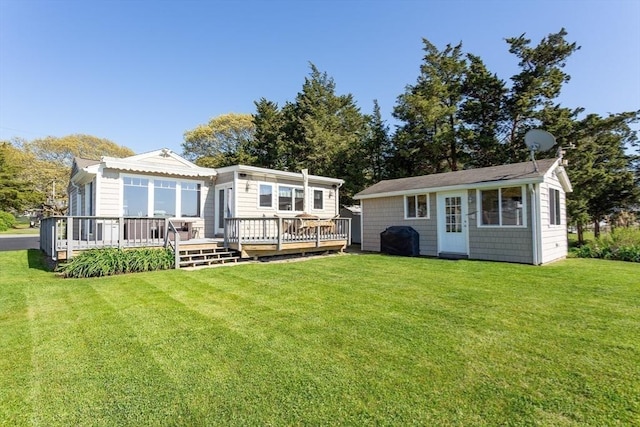 rear view of property featuring a lawn, an outbuilding, and a wooden deck