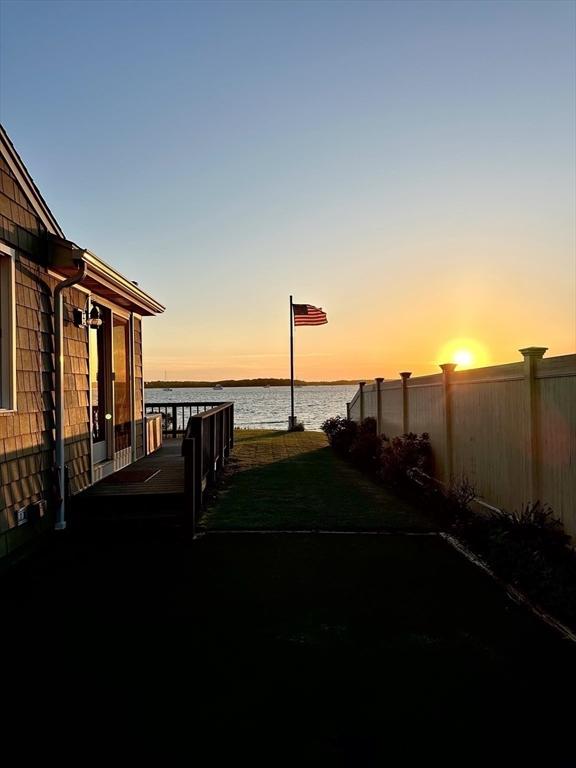 yard at dusk featuring a water view