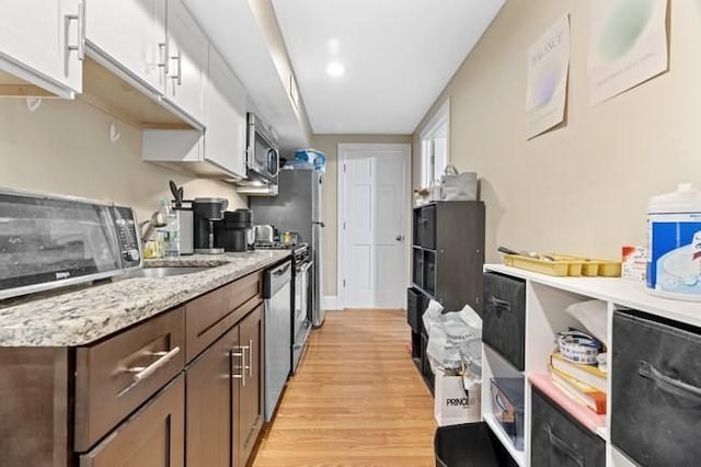 kitchen with light wood-style floors, appliances with stainless steel finishes, dark brown cabinetry, and white cabinetry