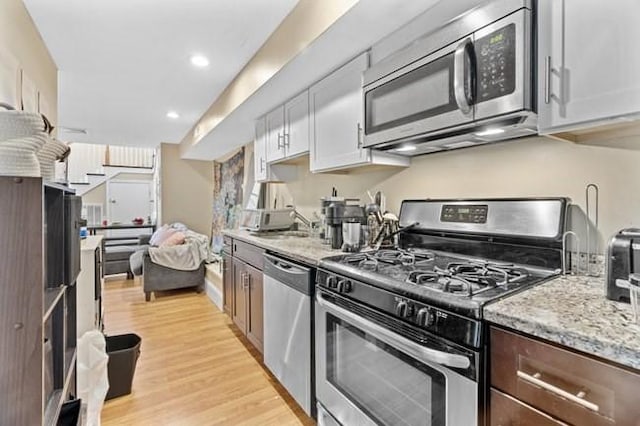 kitchen featuring appliances with stainless steel finishes, light wood-type flooring, light stone countertops, and recessed lighting
