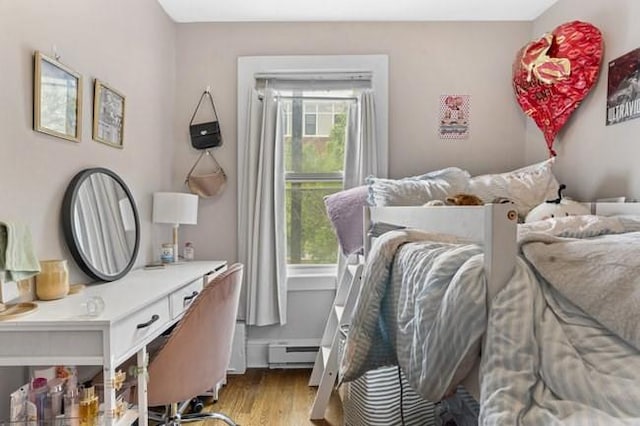 bedroom with a baseboard radiator and wood finished floors