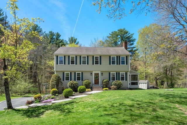 colonial house with a sunroom, a front lawn, and a chimney