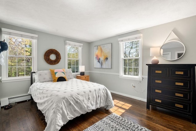 bedroom featuring baseboards, multiple windows, baseboard heating, and dark wood finished floors