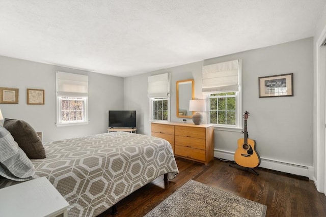 bedroom featuring a baseboard heating unit and dark wood finished floors