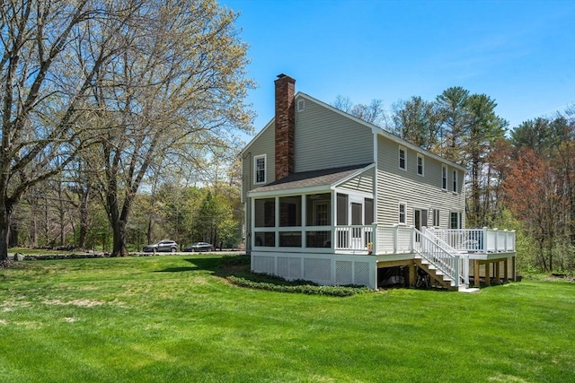 back of property featuring a sunroom, a yard, a chimney, and a deck