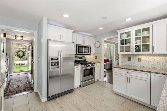 kitchen with a wealth of natural light, stainless steel appliances, tasteful backsplash, and white cabinetry