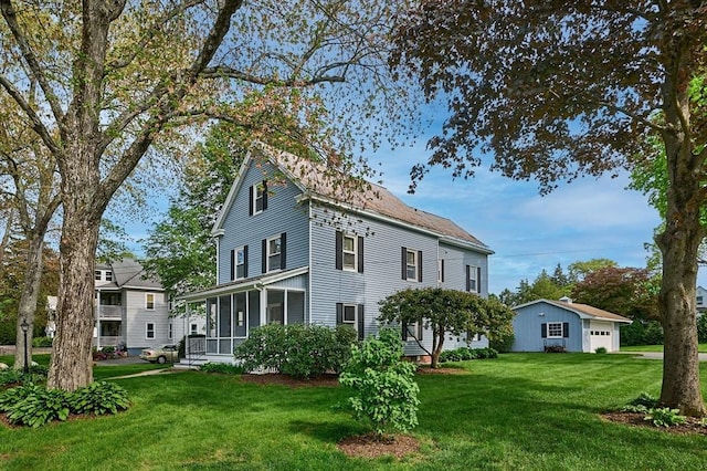 rear view of property featuring a yard, a sunroom, and a garage