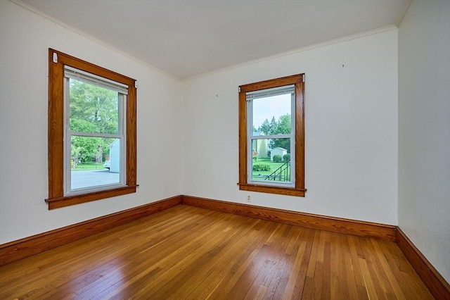 unfurnished room featuring hardwood / wood-style floors, ornamental molding, and baseboards