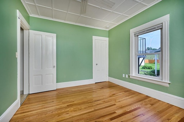 unfurnished bedroom featuring baseboards, light wood-type flooring, and crown molding