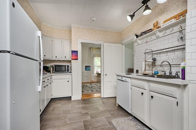 kitchen featuring white appliances, a sink, wallpapered walls, white cabinetry, and light countertops