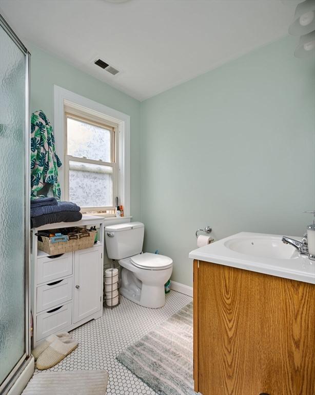 full bath with a stall shower, toilet, baseboards, and vanity