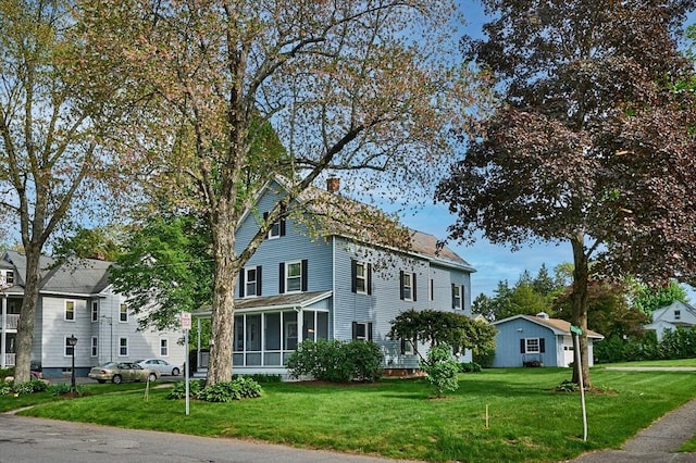 view of front of house with a sunroom, a front yard, and a chimney