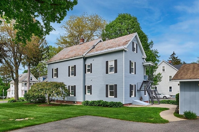 back of property with a yard and a chimney