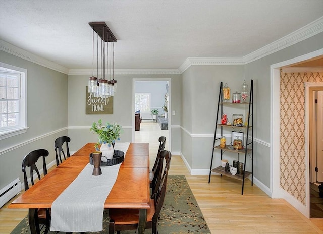 dining room featuring a baseboard heating unit, light wood finished floors, baseboards, and a healthy amount of sunlight