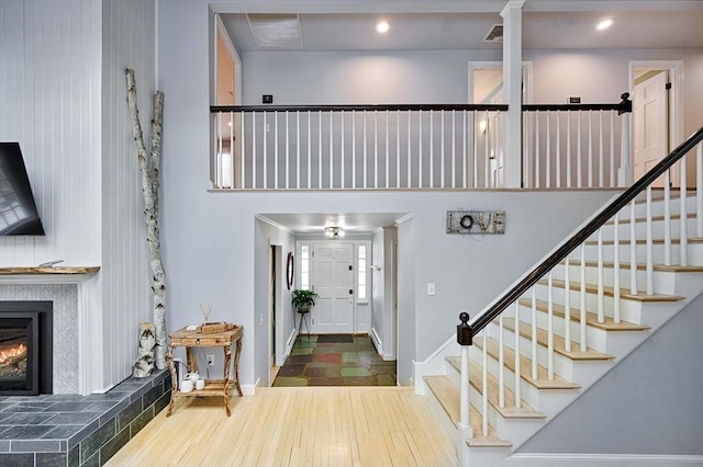 foyer entrance featuring stairs, visible vents, a tiled fireplace, and wood finished floors