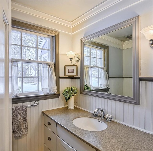 bathroom featuring ornamental molding, visible vents, a wainscoted wall, and vanity