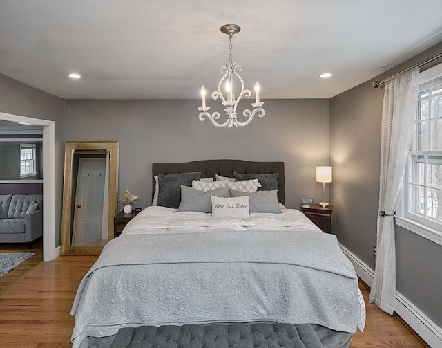 bedroom featuring baseboards, baseboard heating, light wood-style floors, a baseboard heating unit, and recessed lighting