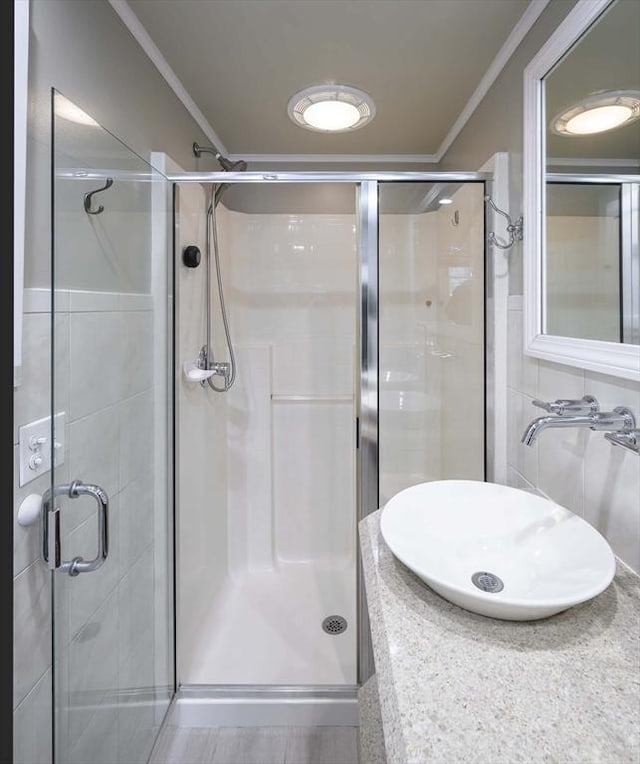 bathroom featuring ornamental molding, a sink, and a shower stall