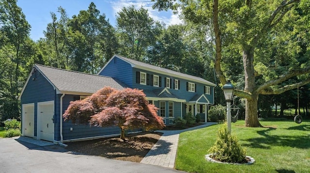 view of front of home with a garage, a front lawn, roof with shingles, and aphalt driveway