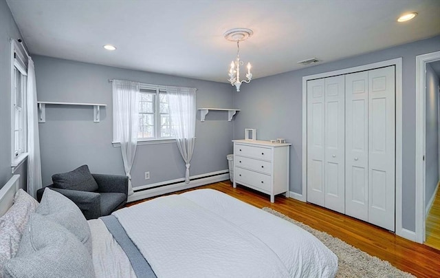 bedroom featuring baseboards, visible vents, wood finished floors, a baseboard heating unit, and recessed lighting