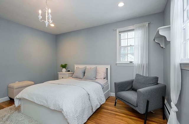 bedroom with recessed lighting, wood finished floors, an inviting chandelier, and baseboards