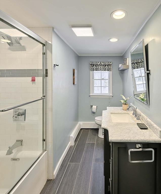 full bath featuring toilet, vanity, ornamental molding, and wood finish floors