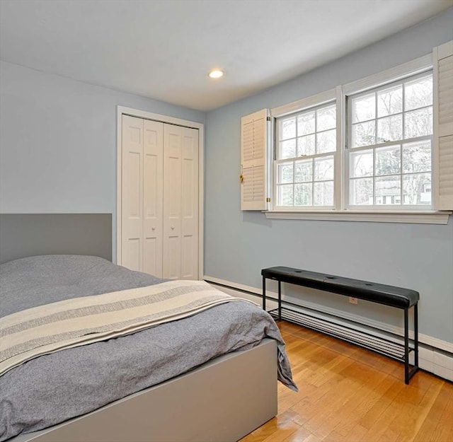 bedroom with recessed lighting, a closet, light wood-style flooring, and baseboard heating