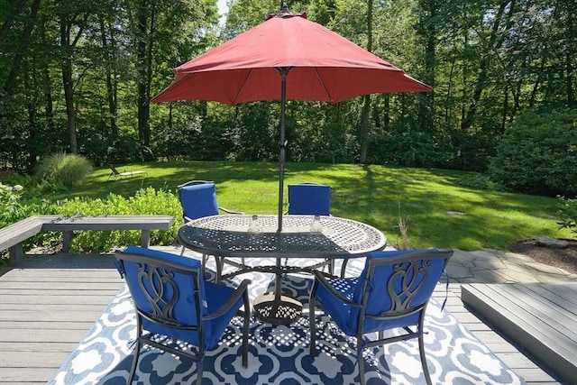 wooden deck featuring outdoor dining area and a lawn