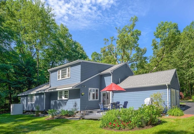 back of property with a garage, a yard, and a shingled roof