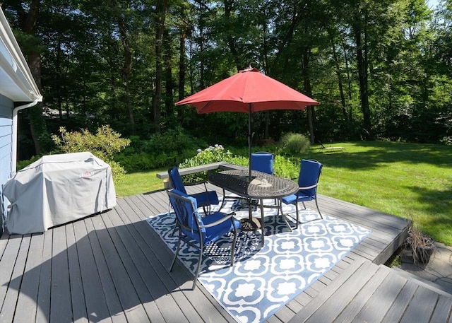 wooden deck featuring grilling area, a lawn, and outdoor dining space