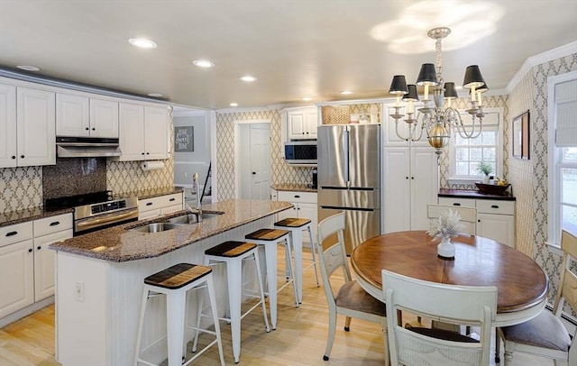 kitchen featuring appliances with stainless steel finishes, a sink, under cabinet range hood, and wallpapered walls