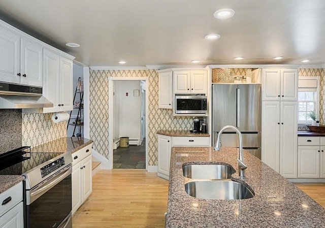 kitchen with appliances with stainless steel finishes, a sink, under cabinet range hood, and wallpapered walls