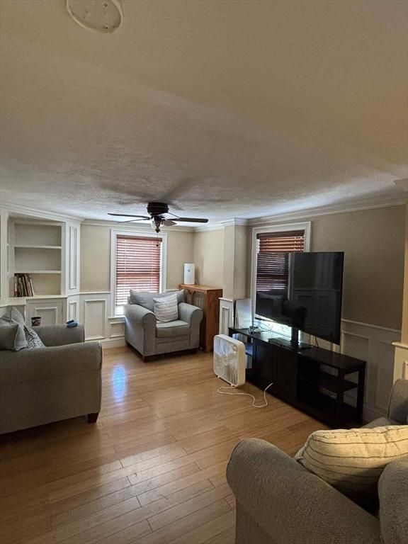 44 Cherry St Unit 2, Swampscott, MA 01907 - living room featuring a decorative wall, built in shelves, ceiling fan, ornamental molding, and wood finished floors