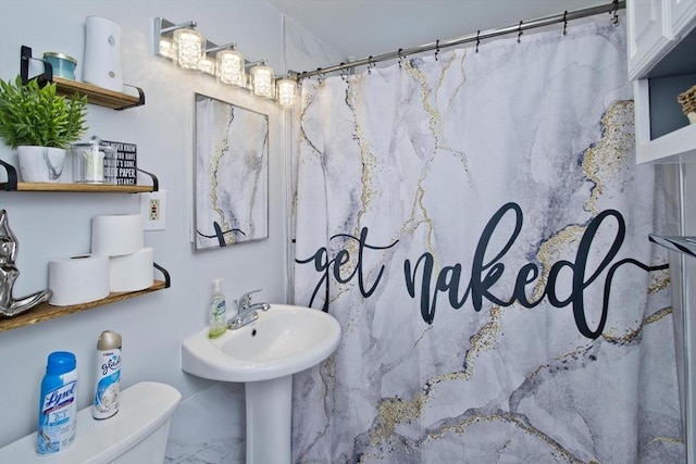 bathroom with toilet, marble finish flooring, and a shower with shower curtain