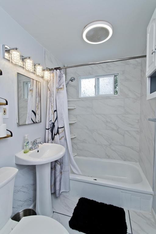 bathroom featuring marble finish flooring, toilet, and shower / tub combo