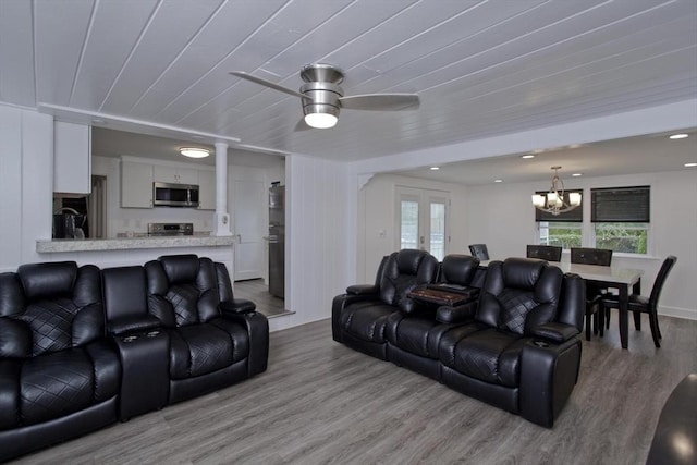 living area with a chandelier, wood finished floors, healthy amount of natural light, and a ceiling fan