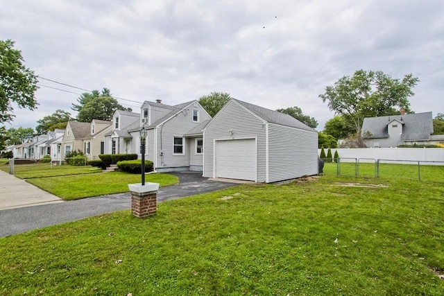 view of front of property featuring a residential view, asphalt driveway, and an outbuilding