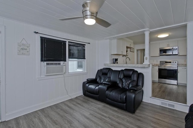 living room with wood finished floors, a ceiling fan, cooling unit, and baseboards
