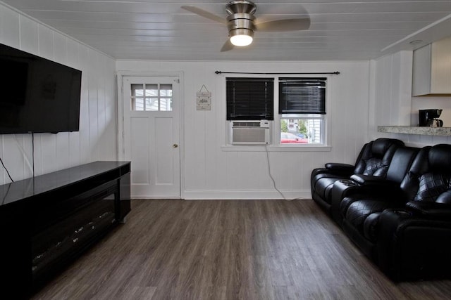 living room with dark wood-style flooring, cooling unit, baseboards, a ceiling fan, and crown molding