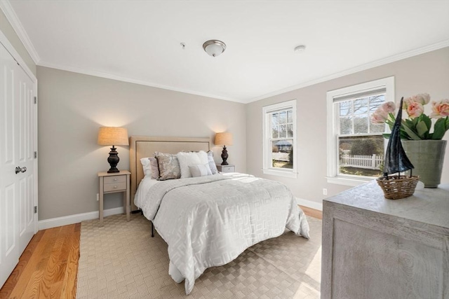 bedroom featuring crown molding, light wood finished floors, and baseboards